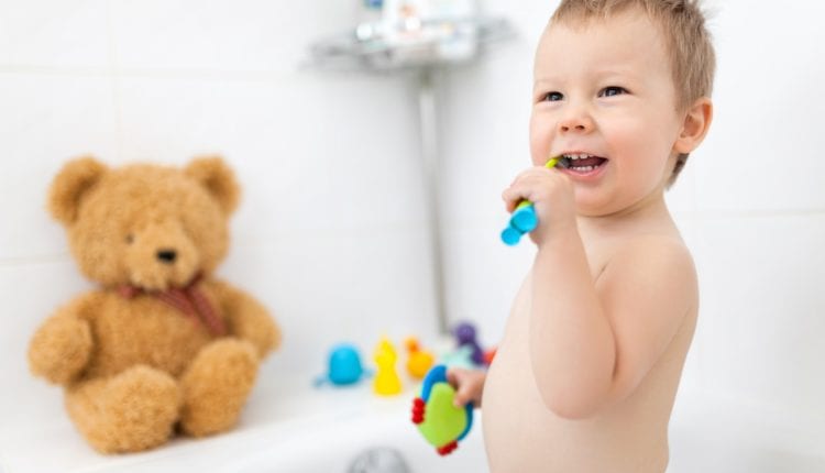 Adorable child learing how to brush his teeth