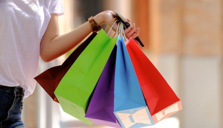 Young girl shopper hold several shopping bags on hand.
