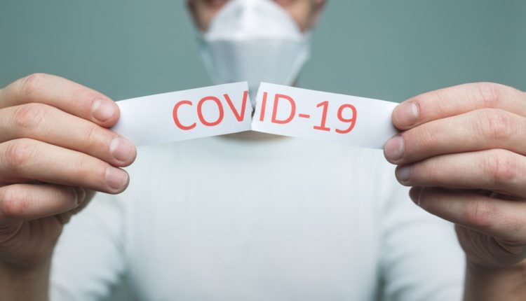 Man wearing a respiratory mask, holding the Coronavirus Covid-19 sign